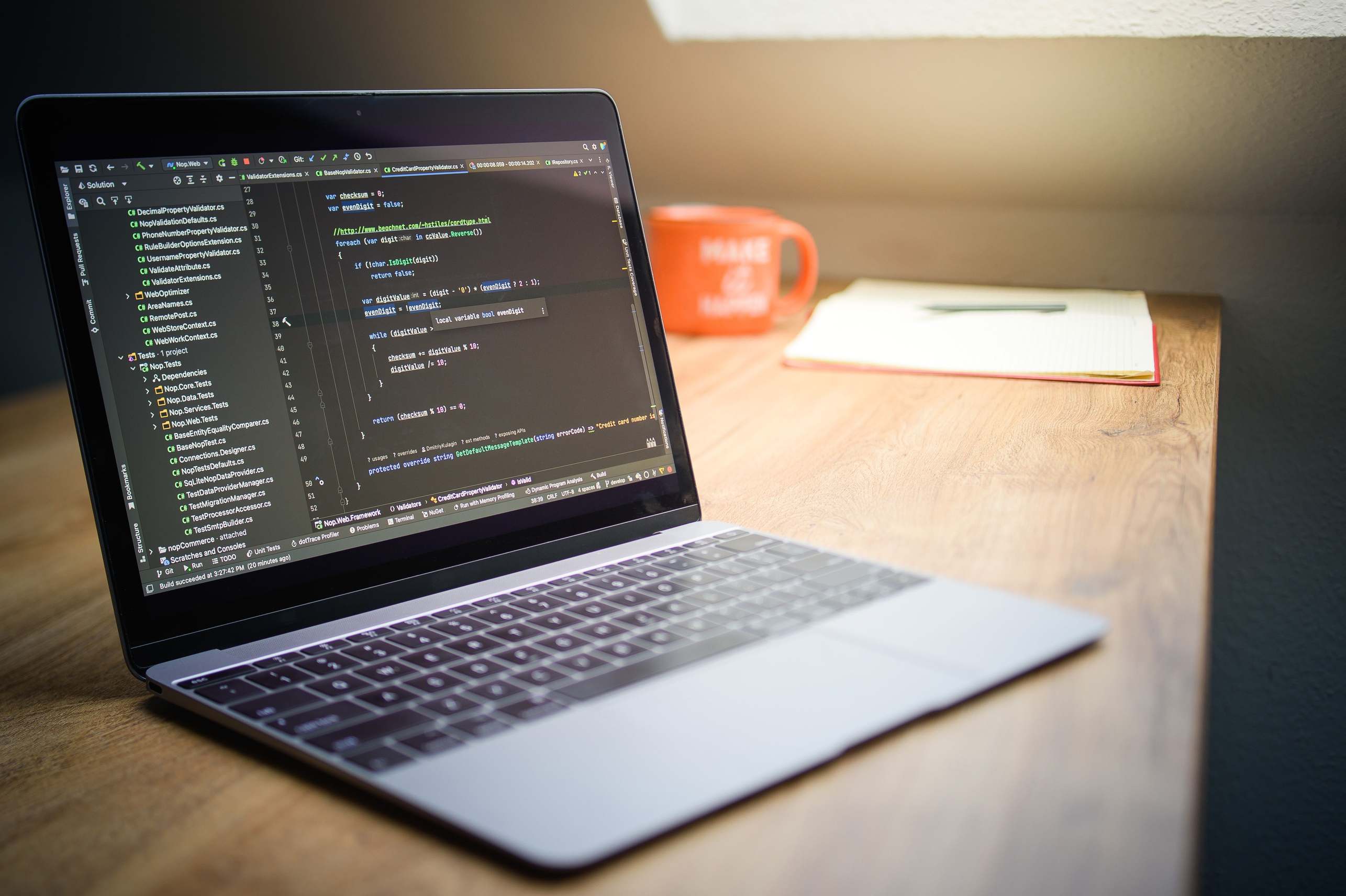 Wide view of a developer workspace with laptop and notes on a desk